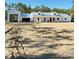 Exterior view of a modern farmhouse with a detached garage surrounded by raw land and clear blue skies at 12009 Sw 61St Place Road, Ocala, FL 34481