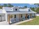 Beautiful white farmhouse exterior with metal roof, wooden columns, and manicured landscaping at 12009 Sw 61St Place Road, Ocala, FL 34481