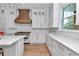 Elegant kitchen featuring white cabinetry, quartz countertops, a stylish range hood, and stainless steel appliances at 12009 Sw 61St Place Road, Ocala, FL 34481