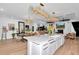 Open-concept living room boasts elegant chandeliers, a kitchen island, and a comfortable seating area with fireplace at 12009 Sw 61St Place Road, Ocala, FL 34481