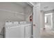 Efficient laundry room featuring side-by-side washer and dryer and overhead shelving for storage at 4457 Le Reve Ct, Kissimmee, FL 34746