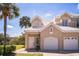 Charming townhouse featuring a two-car garage, white tile roof, and tropical landscaping at 7700 Carriage Homes Dr # 4, Orlando, FL 32819