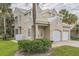 Inviting two-story home with a two-car garage, manicured lawn, mature landscaping, and white tile roof at 7700 Carriage Homes Dr # 4, Orlando, FL 32819