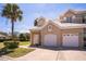 Inviting home featuring a two-car garage, neutral stucco exterior, and a well-maintained front lawn with palm tree at 7700 Carriage Homes Dr # 4, Orlando, FL 32819