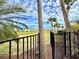 Serene backyard view overlooking a green lawn and colorful homes, framed by swaying palm trees and an iron fence at 8033 Surf St, Kissimmee, FL 34747