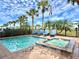 A luxurious pool and hot tub surrounded by palm trees and comfortable lounge chairs under a sunny sky at 8033 Surf St, Kissimmee, FL 34747