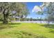 Backyard with lush green grass and a mature tree overlooking a tranquil lake at 119 Lake Dr, Oviedo, FL 32765