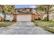 Two story home with neutral toned siding and brick accents, featuring an attached two car garage and mature landscaping at 1000 Manigan Ave, Oviedo, FL 32765