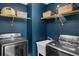 Modern laundry room with blue walls, shelving, and front loading washer and dryer at 2129 Victoria Glen Dr, Sanford, FL 32773