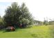 View of the backyard with large trees, green lawn, and a utility vehicle at 3555 E Johnson Ave, Haines City, FL 33844