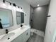Bathroom featuring dual vanities, a gray-tiled shower, and sleek black fixtures at 6421 Sw 151St Loop, Ocala, FL 34473