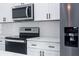 Close-up of kitchen features stainless appliances, white cabinets, and speckled countertops at 6421 Sw 151St Loop, Ocala, FL 34473