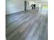 Spacious living room featuring modern gray wood-look flooring and a view of the kitchen at 6421 Sw 151St Loop, Ocala, FL 34473