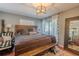 An elegant bedroom featuring a wooden bed frame, wooden bench, and decorative mirror at 3076 Crane Strand Dr, Winter Park, FL 32792