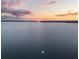Wide aerial shot of a lake at sunset with a sailboat in the distance, casting a serene and peaceful scene at 12550 Lakeshore Dr, Clermont, FL 34711