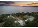 Panoramic aerial view of a lakeside property with homes surrounded by trees, featuring a picturesque sunset at 12550 Lakeshore Dr, Clermont, FL 34711