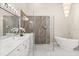 Elegant bathroom featuring double vanity, glass enclosed shower, and a free-standing bathtub at 12550 Lakeshore Dr, Clermont, FL 34711