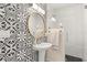 Stylish bathroom showcasing black and white patterned tile, gold accents, and a sleek, round mirror at 12550 Lakeshore Dr, Clermont, FL 34711