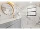 Bright bathroom featuring marble tile, modern vanity, and round mirror at 12550 Lakeshore Dr, Clermont, FL 34711