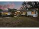 Modern one-story home with tasteful landscaping and an inviting entrance, bathed in the soft glow of evening at 12550 Lakeshore Dr, Clermont, FL 34711