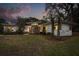 Contemporary one-story home with updated landscaping and hardscaping, illuminated by the evening light at 12550 Lakeshore Dr, Clermont, FL 34711