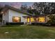 Well-lit modern home featuring a manicured lawn, mature landscaping, and large windows at 12550 Lakeshore Dr, Clermont, FL 34711