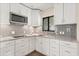Bright kitchen with white cabinets, granite countertops, and stainless steel microwave at 12550 Lakeshore Dr, Clermont, FL 34711