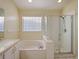 Bathroom boasting a soaking tub, glass shower, single vanity, and large window at 12924 Lower River Blvd, Orlando, FL 32828