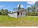 Backyard view featuring the home's exterior, lush lawn, and a backdrop of trees at 13516 Sw 78 Pl, Dunnellon, FL 34432