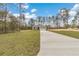 View of the front exterior shows a modern house with well-maintained lawn and a long driveway in a wooded area at 13516 Sw 78 Pl, Dunnellon, FL 34432