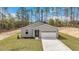 A modern single-story house with well-maintained lawn and a long driveway, surrounded by tall trees and nature at 13516 Sw 78 Pl, Dunnellon, FL 34432