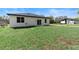 Spacious backyard with lush green grass and a charming white home with a black roof, complemented by mature trees at 205 E 17Th St, Apopka, FL 32703