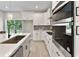 Well-lit kitchen featuring white cabinets, stainless steel appliances, and a view of the lush backyard at 205 E 17Th St, Apopka, FL 32703