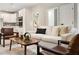 Bright living room with a sofa, chairs, and view into a modern kitchen with white cabinets and stainless appliances at 205 E 17Th St, Apopka, FL 32703