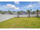 Level backyard with green grass, small palm trees and a tall white privacy fence at 1162 Happy Forest Loop, Deland, FL 32720