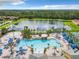 Aerial view of community pool with multiple pools, lounge chairs, gazebo, tennis courts and a large pond surrounded by trees at 2948 Banana Palm Dr, Kissimmee, FL 34747