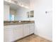 A bathroom featuring double sinks with granite countertops and a large mirror with decorative lighting at 8914 Dove Valley Way, Davenport, FL 33896