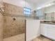 Bathroom featuring a shower with tiled walls, a glass partition, and a decorative accent stripe at 8914 Dove Valley Way, Davenport, FL 33896