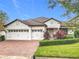 Charming single-story home featuring a three-car garage, brick driveway, clay tile roof and manicured landscaping at 8914 Dove Valley Way, Davenport, FL 33896