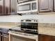 Close-up of stainless steel oven, range, and microwave showcasing granite countertops and dark wood cabinetry at 8914 Dove Valley Way, Davenport, FL 33896