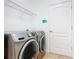 Well-lit laundry room featuring modern washer and dryer, storage shelves and a white door at 8914 Dove Valley Way, Davenport, FL 33896