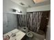 A well-lit bathroom features a vanity, toilet, and shower-tub combination with patterned shower curtain at 2212 Atrium Cir, Orlando, FL 32808