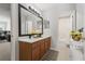 Bright bathroom showcasing double sink vanity with black fixtures and a large framed mirror, adjacent to a bedroom and shower at 698 Mt Pleasant Dr, Ocoee, FL 34761