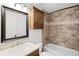 Bathroom featuring a tub-shower with stone tile, vanity, medicine cabinet, and toilet at 1845 Farrington Dr, Lakeland, FL 33809