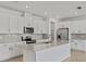Bright kitchen features white cabinetry, stainless steel appliances, and a large center island with counter seating at 2740 Sweet Acacia Dr, Clermont, FL 34711