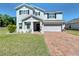 Charming two-story home featuring a well-maintained lawn and brick driveway at 678 Fiddlesticks Dr, Davenport, FL 33837