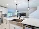 Bright kitchen featuring white cabinets, stainless steel sink, and modern pendant lighting above the island at 678 Fiddlesticks Dr, Davenport, FL 33837