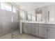 Bathroom features a glass-enclosed shower with tile surround, double vanity, and a bright, natural light at 9097 Wildlight Trl, Wildwood, FL 34785