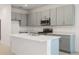 Modern kitchen featuring gray cabinetry, stainless steel appliances, and a center island with sink at 9097 Wildlight Trl, Wildwood, FL 34785