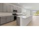 Modern kitchen with gray cabinets, stainless steel appliances, and a large quartz island overlooking the living area at 9097 Wildlight Trl, Wildwood, FL 34785